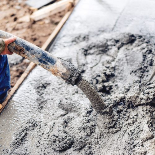 industrial construction workers using automatic pump tube for pouring cement on reinforcement bars